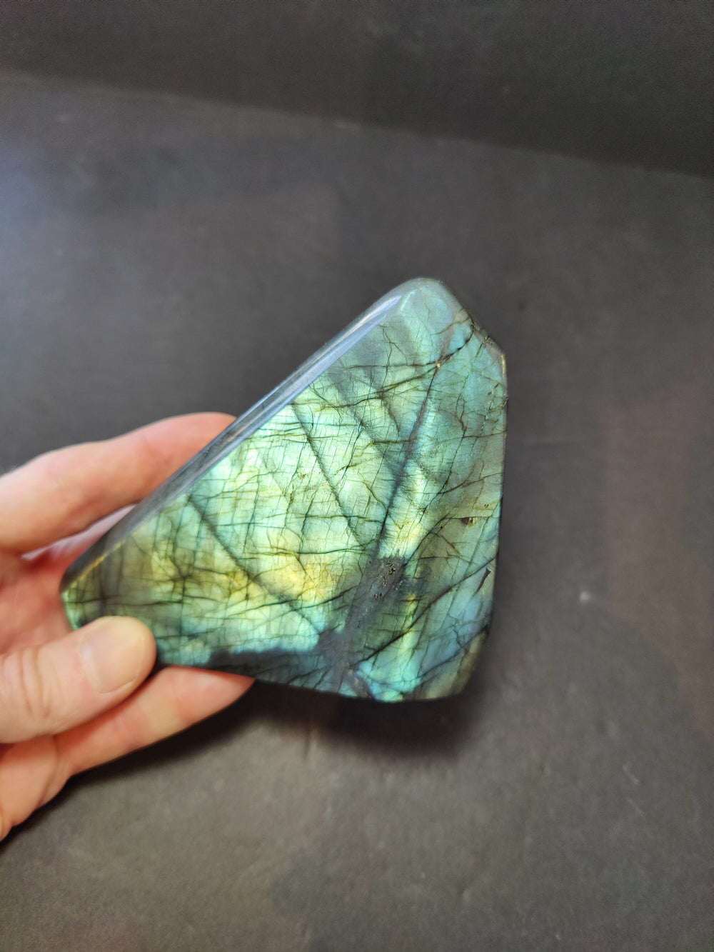 Polished labradorite freeform sculpture, turquoise with fine black lines and blue-gold glow