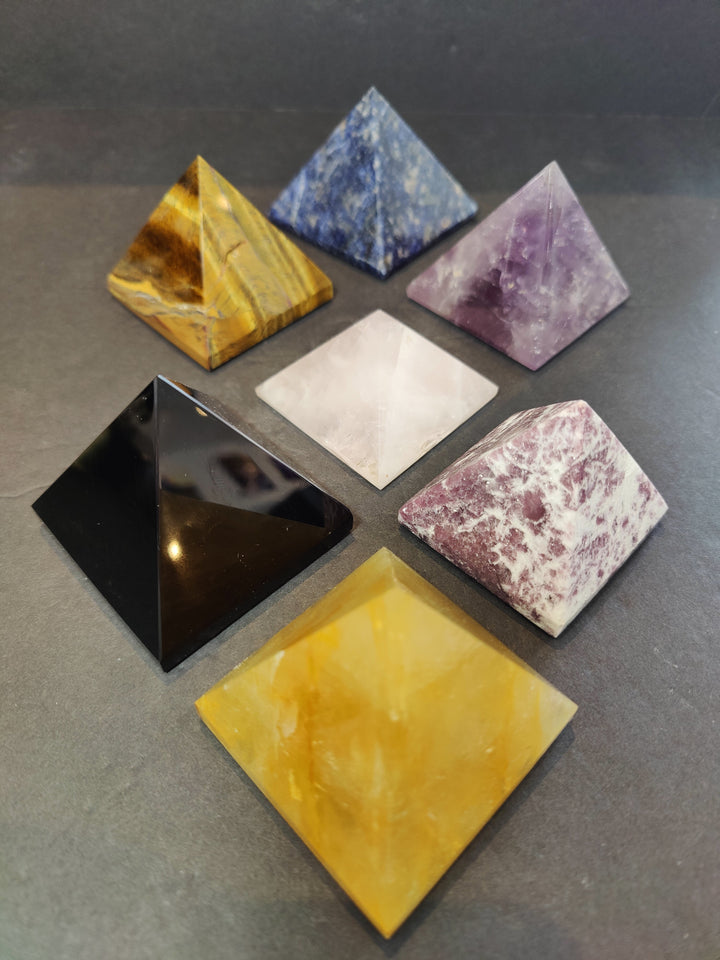 Assorted polished stone pyramid sculptures in yellow, blue, purple, white, black, pink