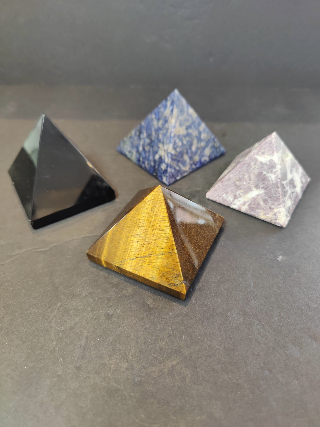 Assorted polished stone pyramid sculptures in black, blue, white, yellow, pale pink
