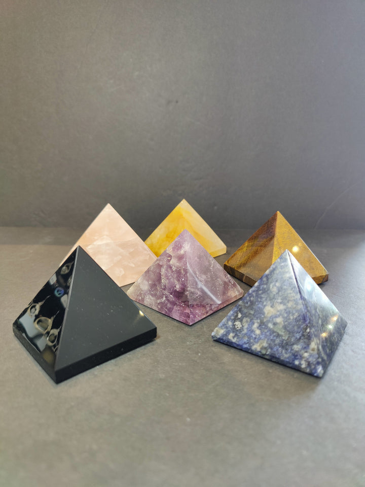 Assorted polished stone pyramid sculptures in black, white, yellow, purple, blue
