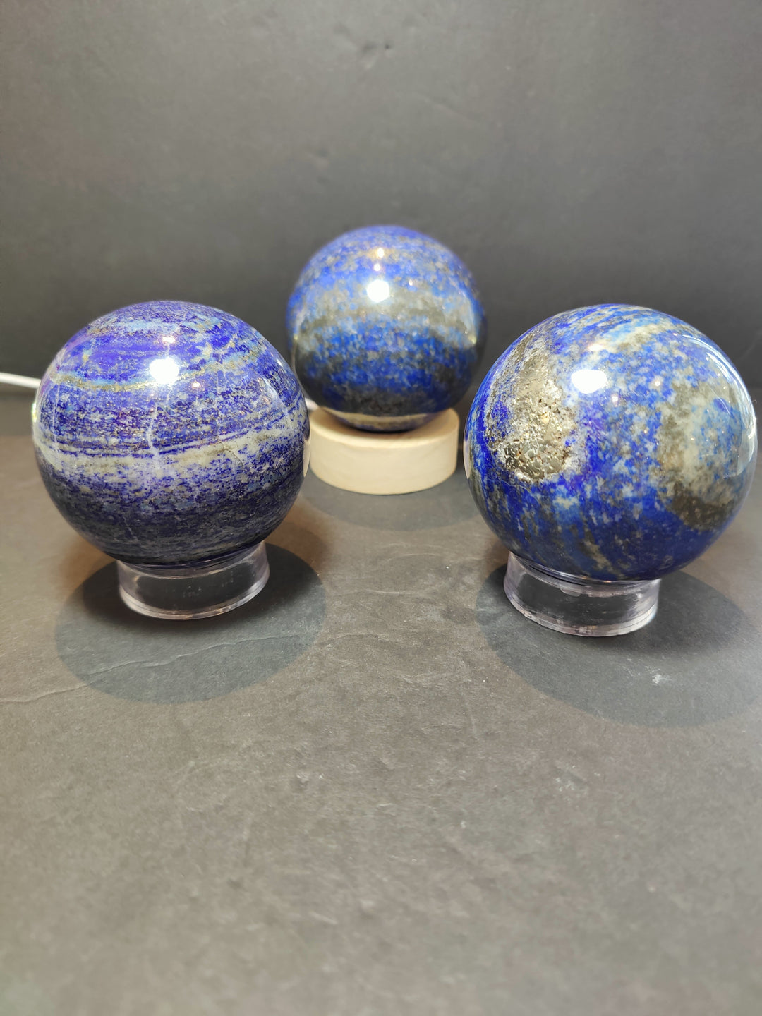 Polished lapis lazuli sphere sculpture set of three, blue-gold speckled stones on stands
