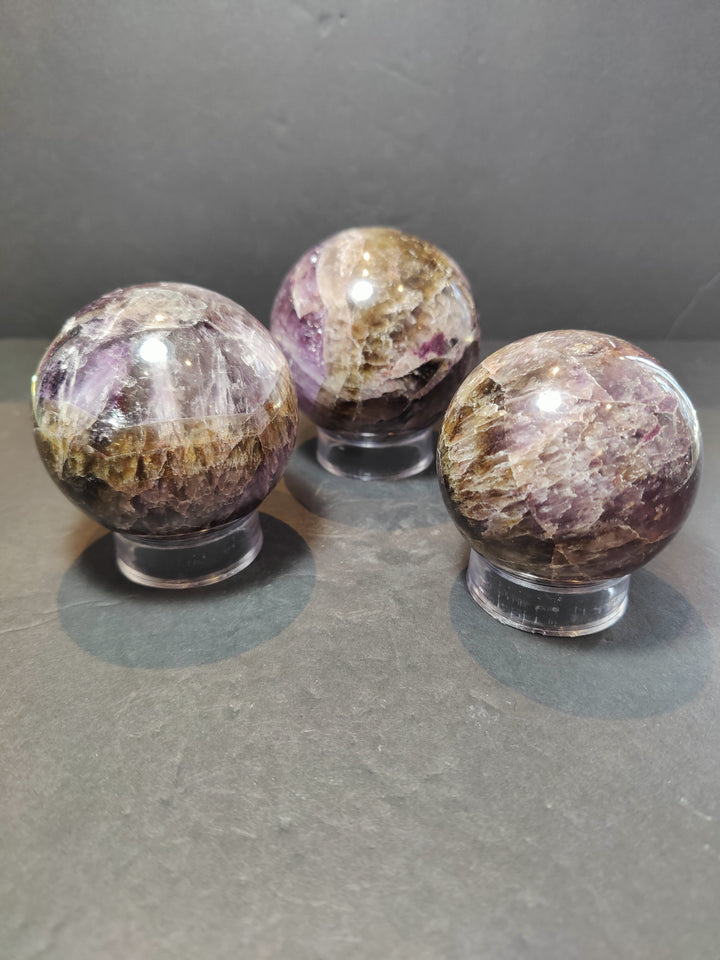 Set of 3 polished purple amethyst crystal spheres with golden bands on metal bases