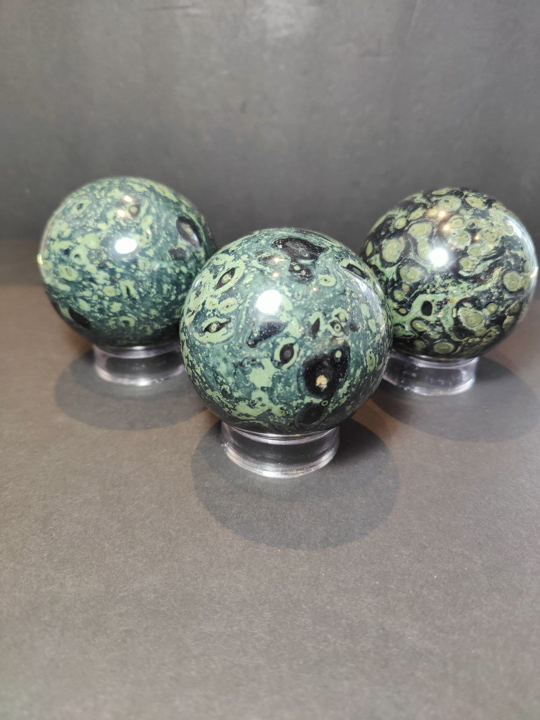 Polished green and black jasper sphere sculpture set on clear acrylic stands