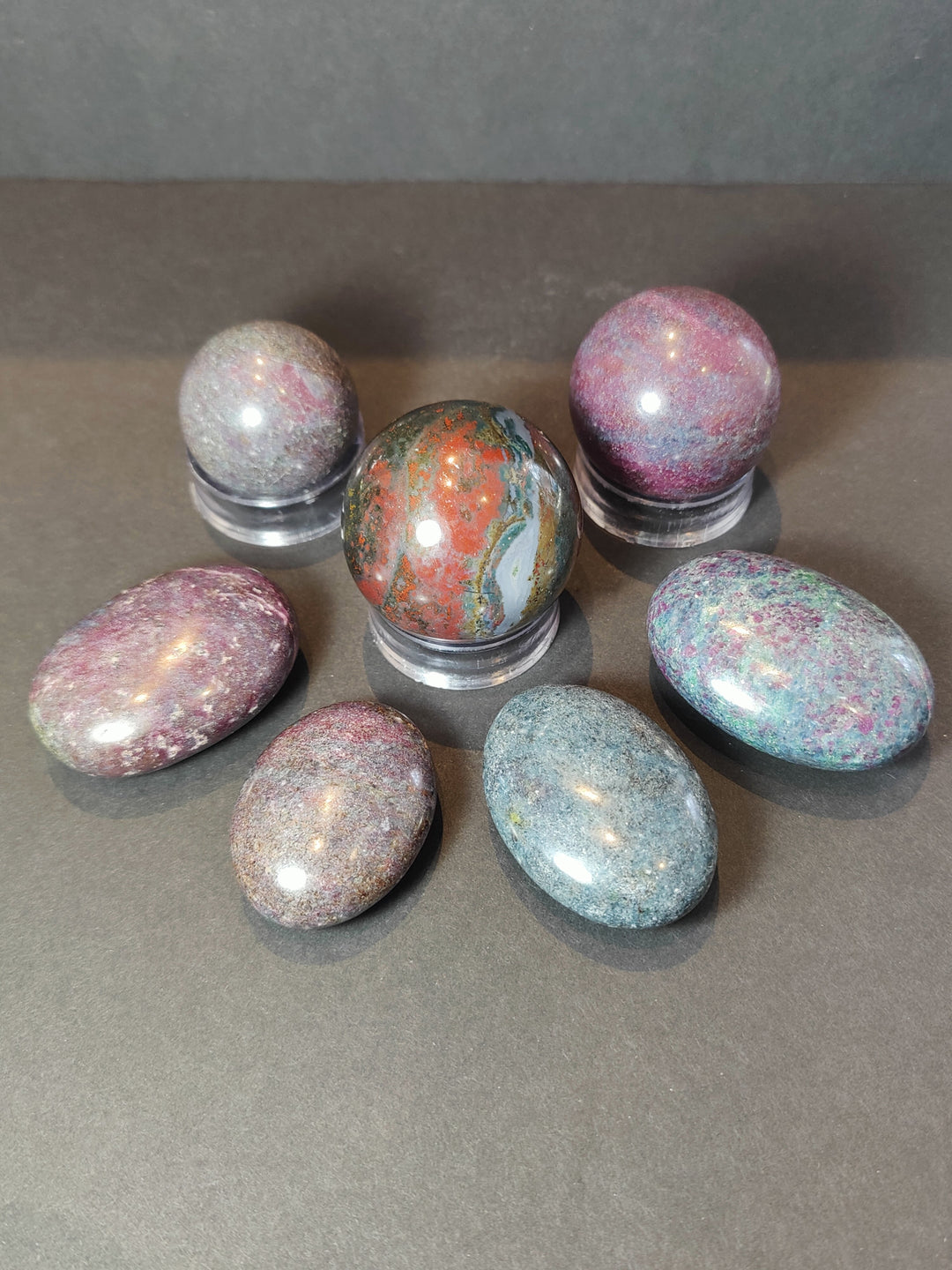 Polished ruby kyanite spheres and palmstones, assorted multicolor stones on metal bases