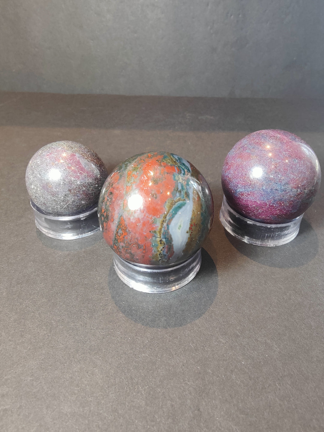 Polished ruby kyanite spheres on clear bases, multicolor purple, pink, and orange tones