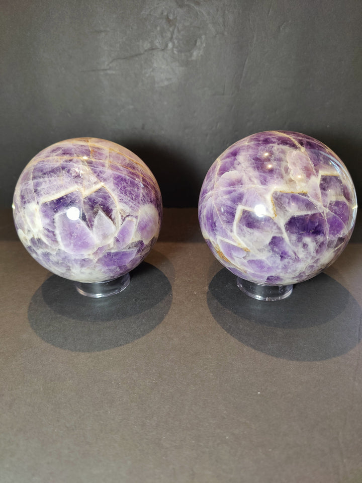 Polished amethyst sphere sculpture on clear base, side-by-side pair