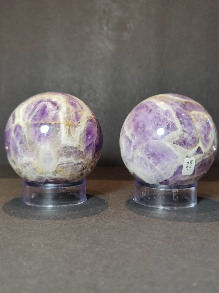 Polished amethyst sphere sculpture on clear base, front view with small sticker