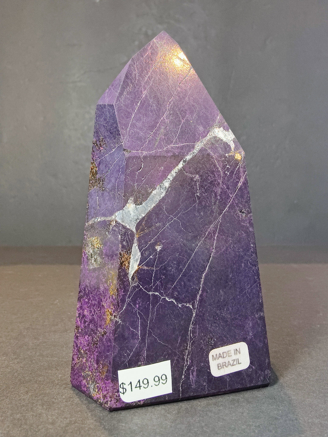 Polished purpurite obelisk tower sculpture with purple crystal surfaces and white streaks.