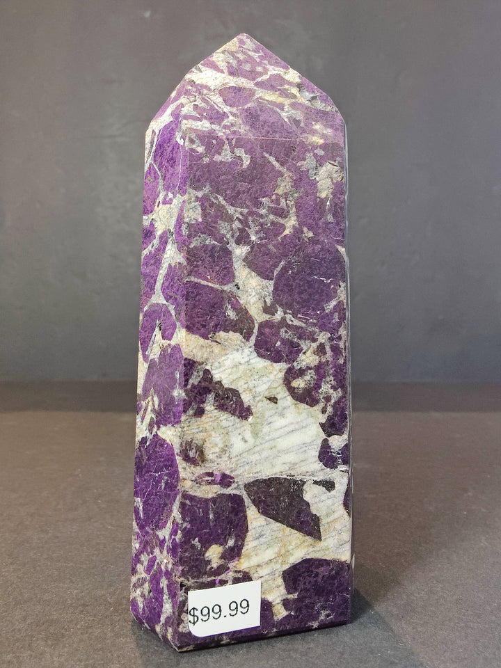Polished purpurite obelisk tower sculpture, tall purple crystal with lighter white patches.