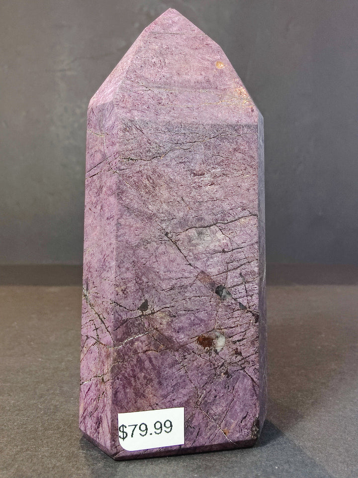 Polished purpurite obelisk tower sculpture in light purple with fine veining and dark lines.