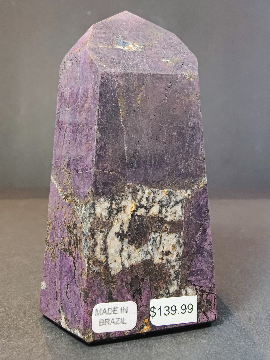 Polished purpurite obelisk tower sculpture, purple with yellow-gold sparkle and white band.