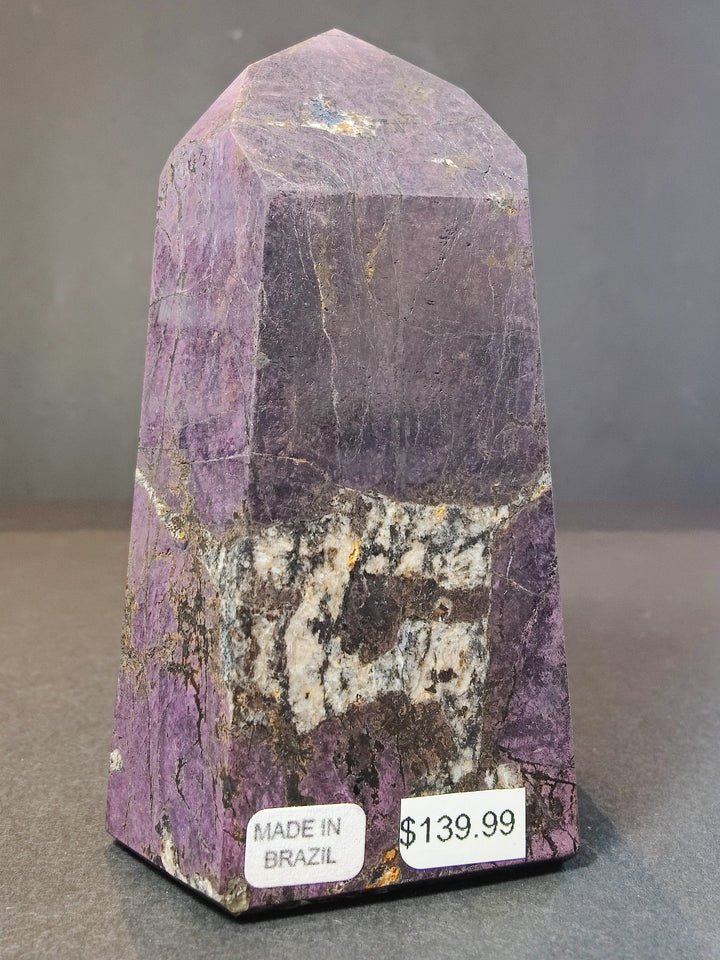 Polished purpurite obelisk tower sculpture, purple with yellow-gold sparkle and white band.