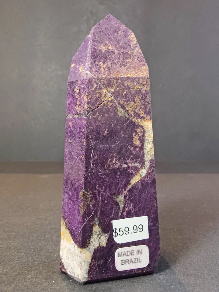 Polished purpurite obelisk tower sculpture, purple crystal with white streaks and dark facets.