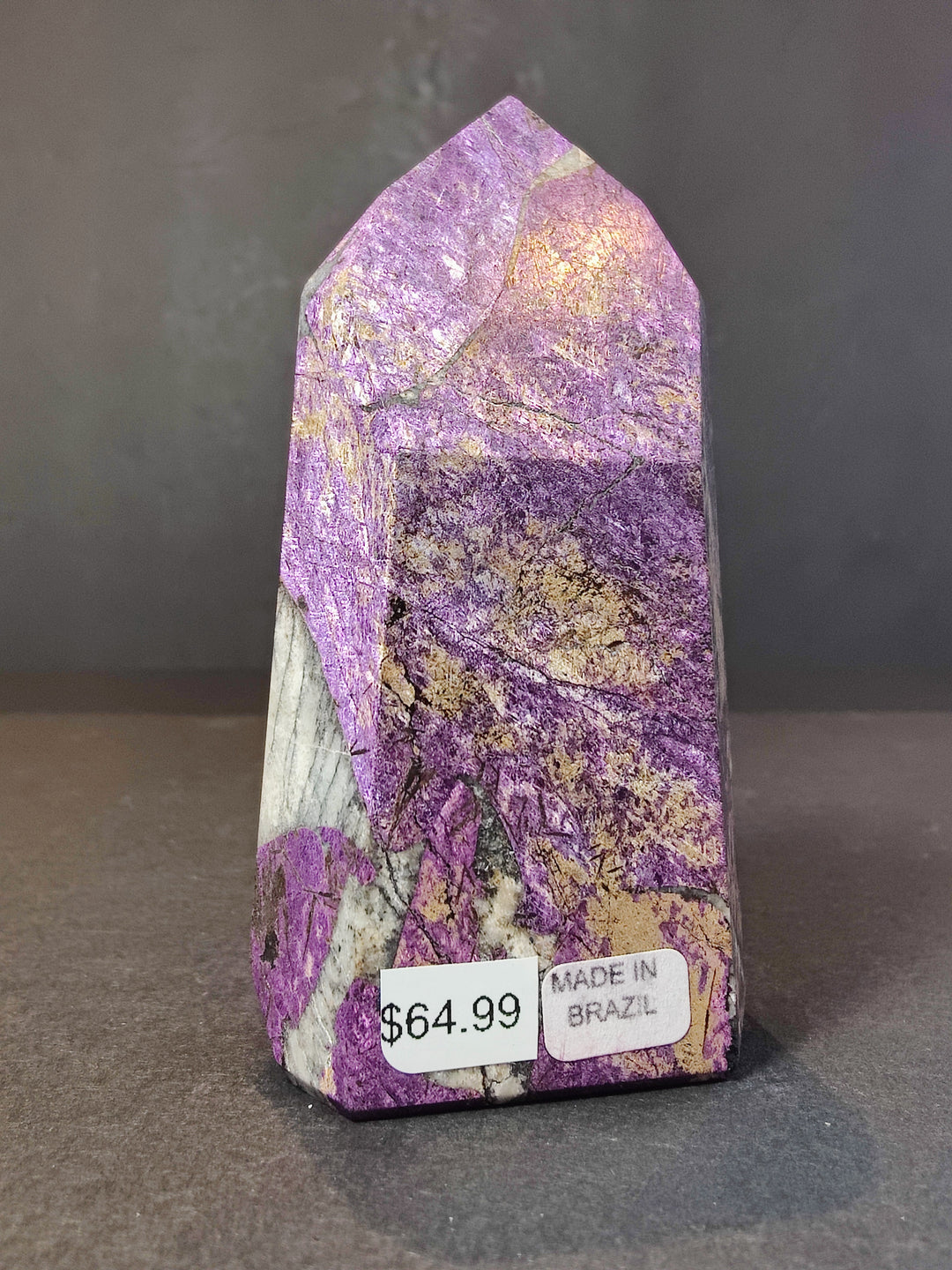 Polished purpurite obelisk tower sculpture with glittery purple top and white base edge.
