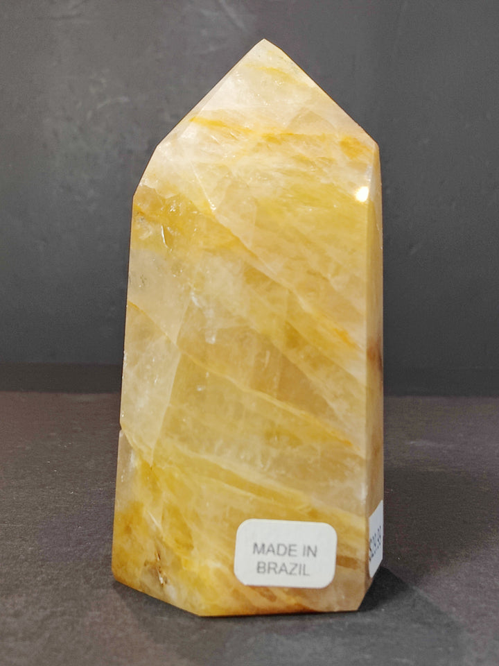 Polished honey-yellow quartz obelisk tower sculpture with natural crystal lines