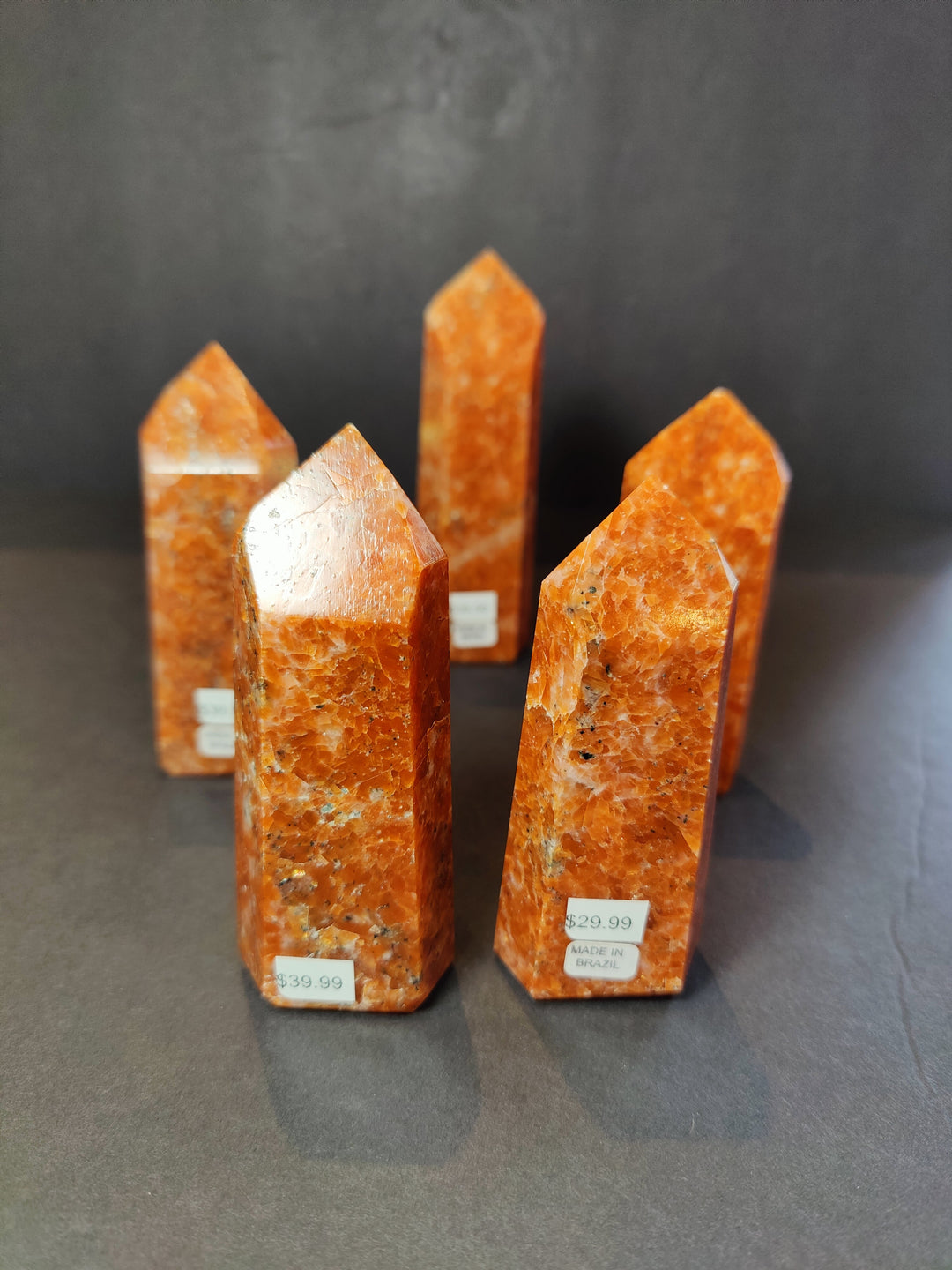Polished sunstone obelisk tower sculpture, orange with faceted natural texture