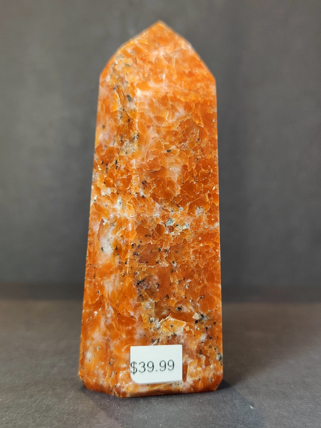 Tall polished sunstone obelisk tower, orange with natural mineral speckles