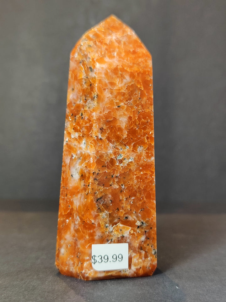 Tall polished sunstone obelisk tower, orange with natural mineral speckles