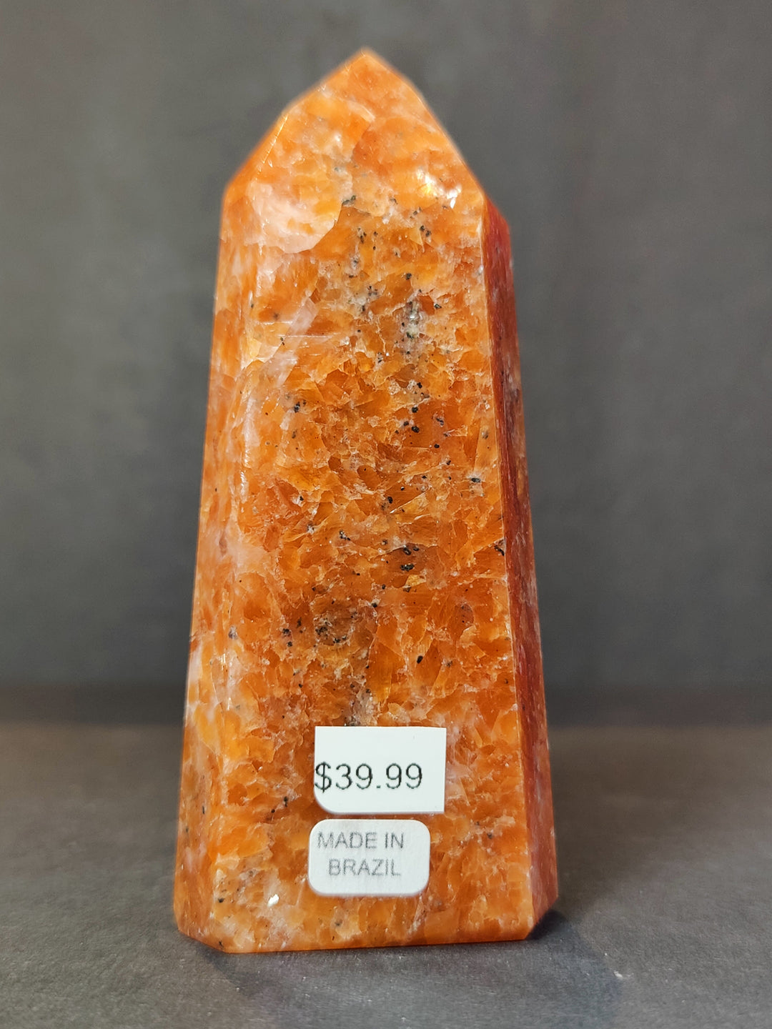 Polished sunstone obelisk tower sculpture, orange mineral texture, front label