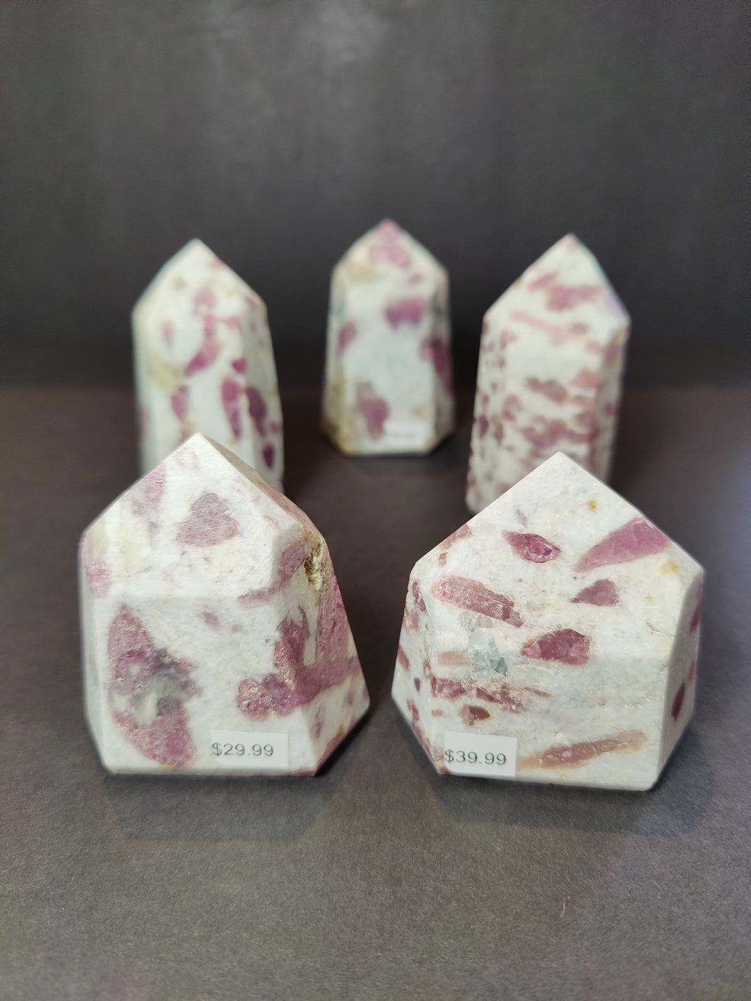 Polished quartz obelisk tower with pink rubellite speckles on a faceted point
