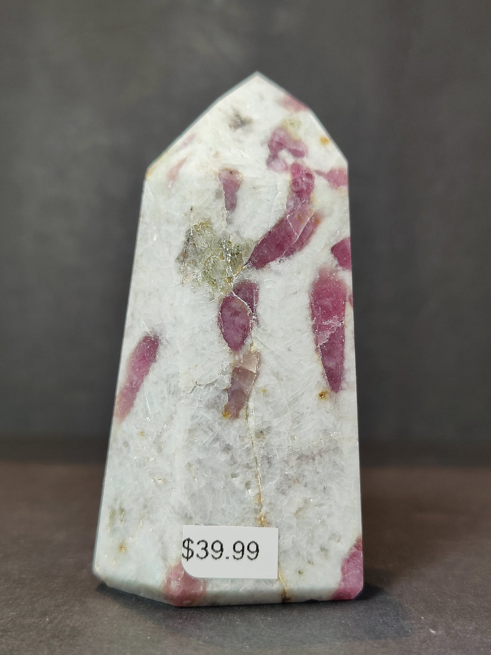 Tall polished quartz obelisk tower with scattered magenta-pink mineral inclusions