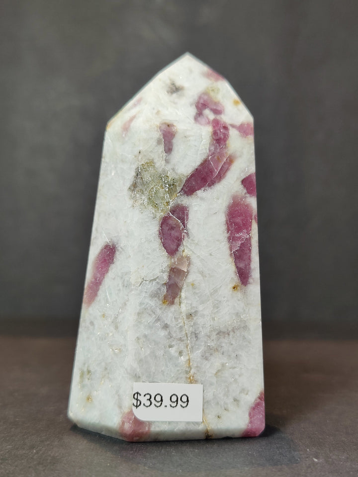 Tall polished quartz obelisk tower with scattered magenta-pink mineral inclusions