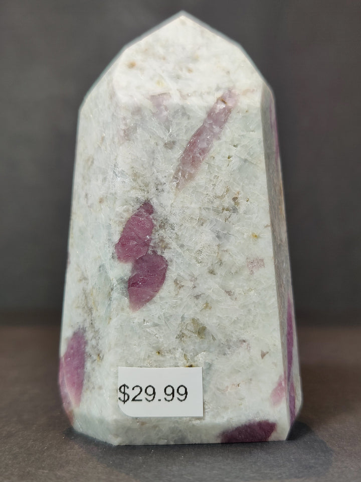 Polished quartz obelisk tower with large pink mineral patches and subtle sparkles