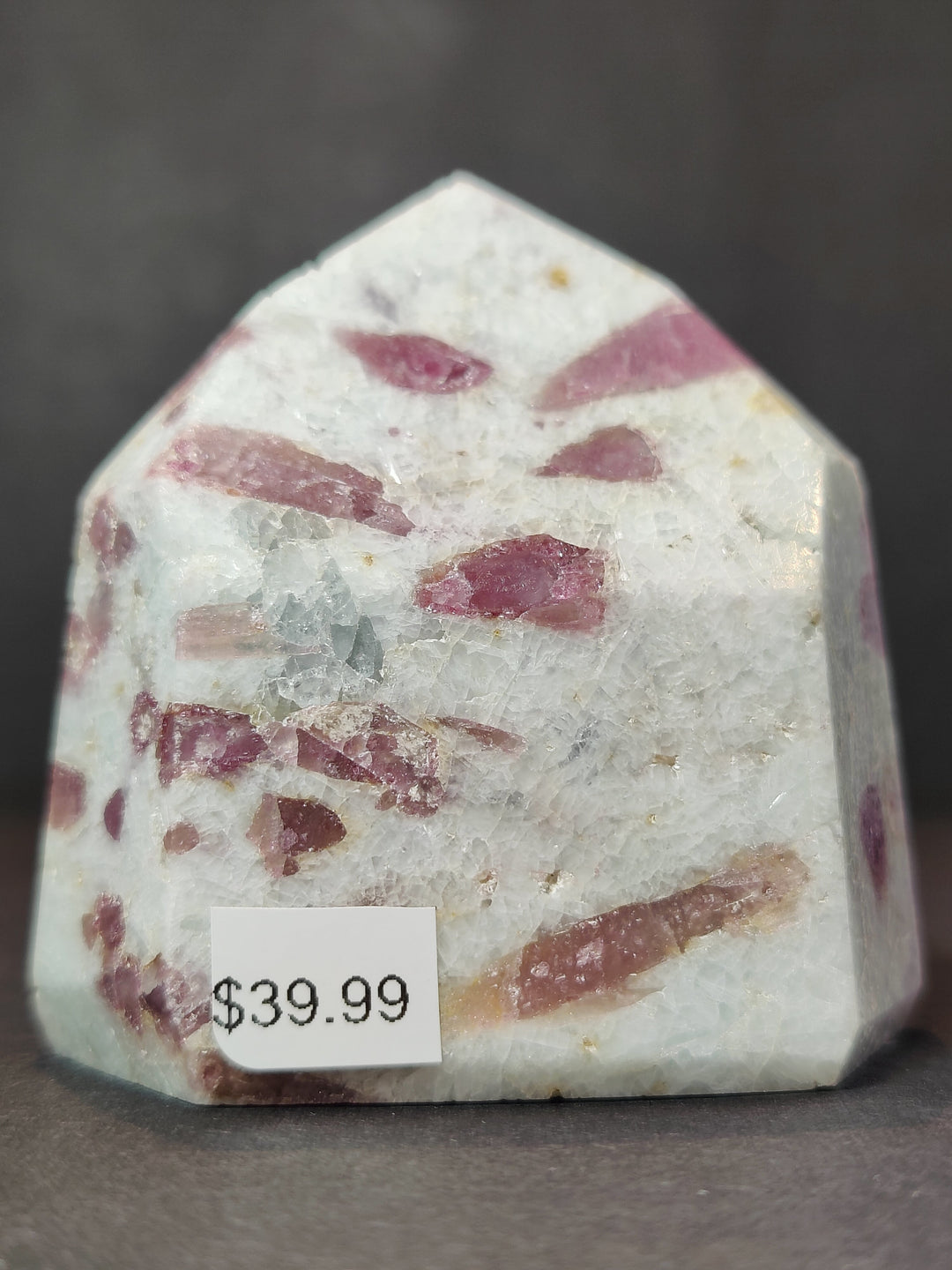Polished quartz obelisk tower with dense pink striations and flecks across the face