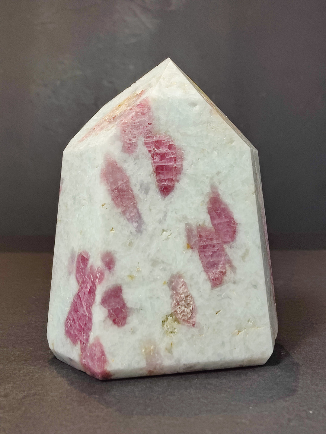 Polished quartz obelisk tower with vivid pink triangular and teardrop-like inclusions