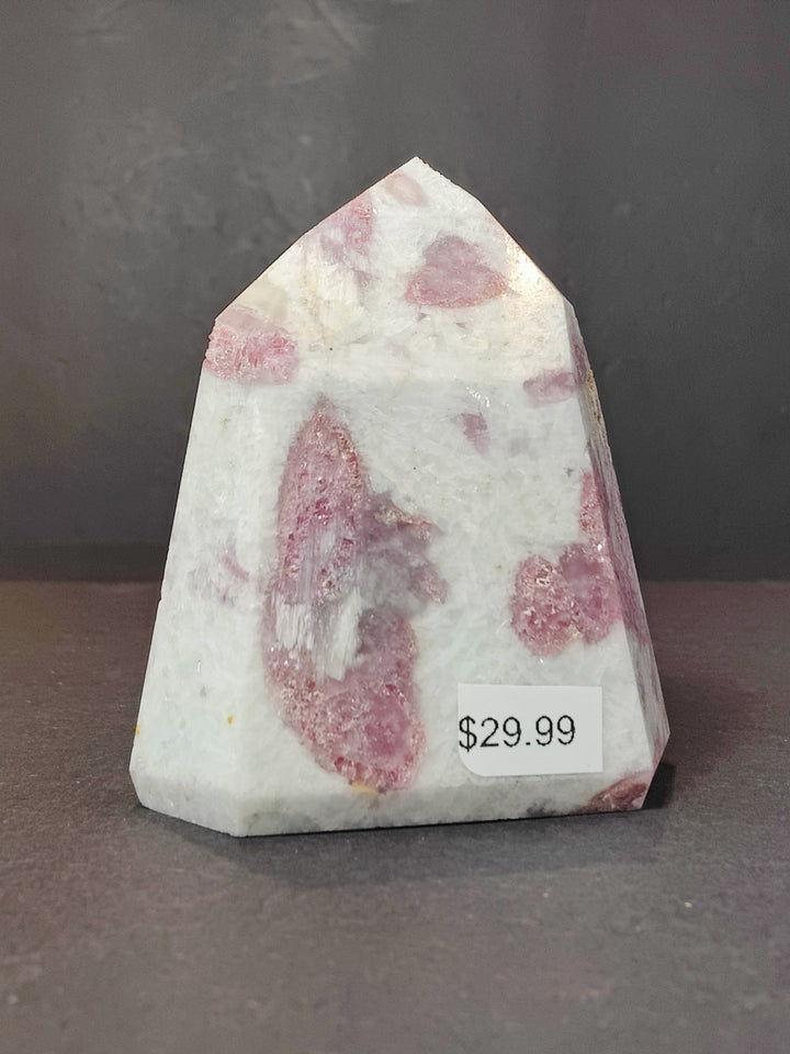 Polished quartz obelisk tower with multiple pink druzy clusters and scattered flecks