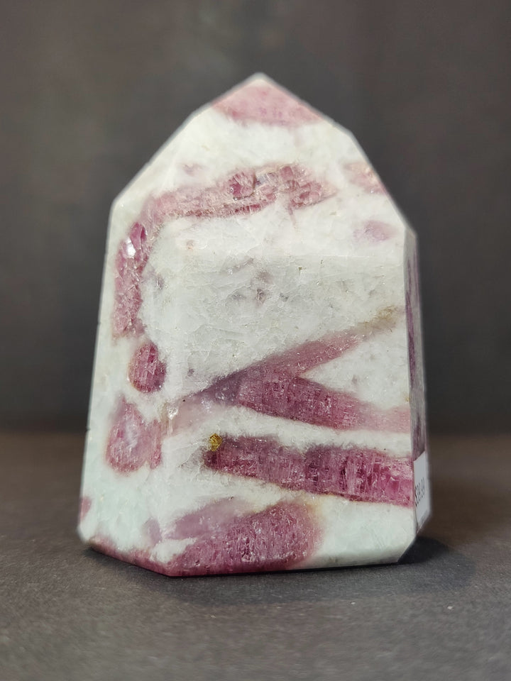 Polished quartz obelisk tower with bold pink bands across the front