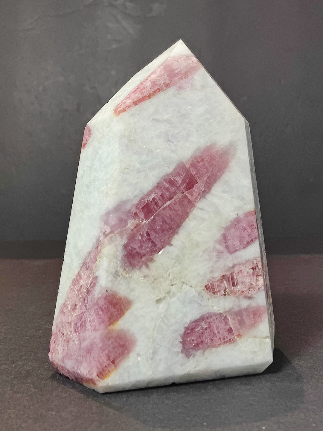 Polished quartz obelisk tower with pink striated mineral layers and light veining