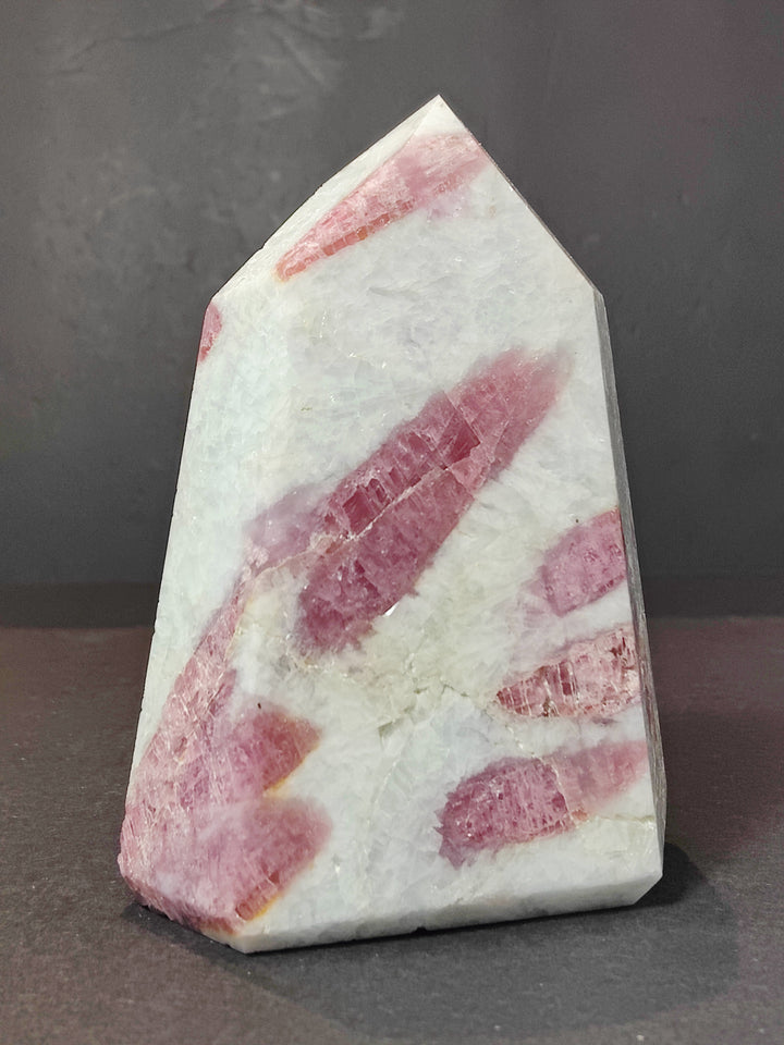Polished quartz obelisk tower with pink striated mineral layers and light veining