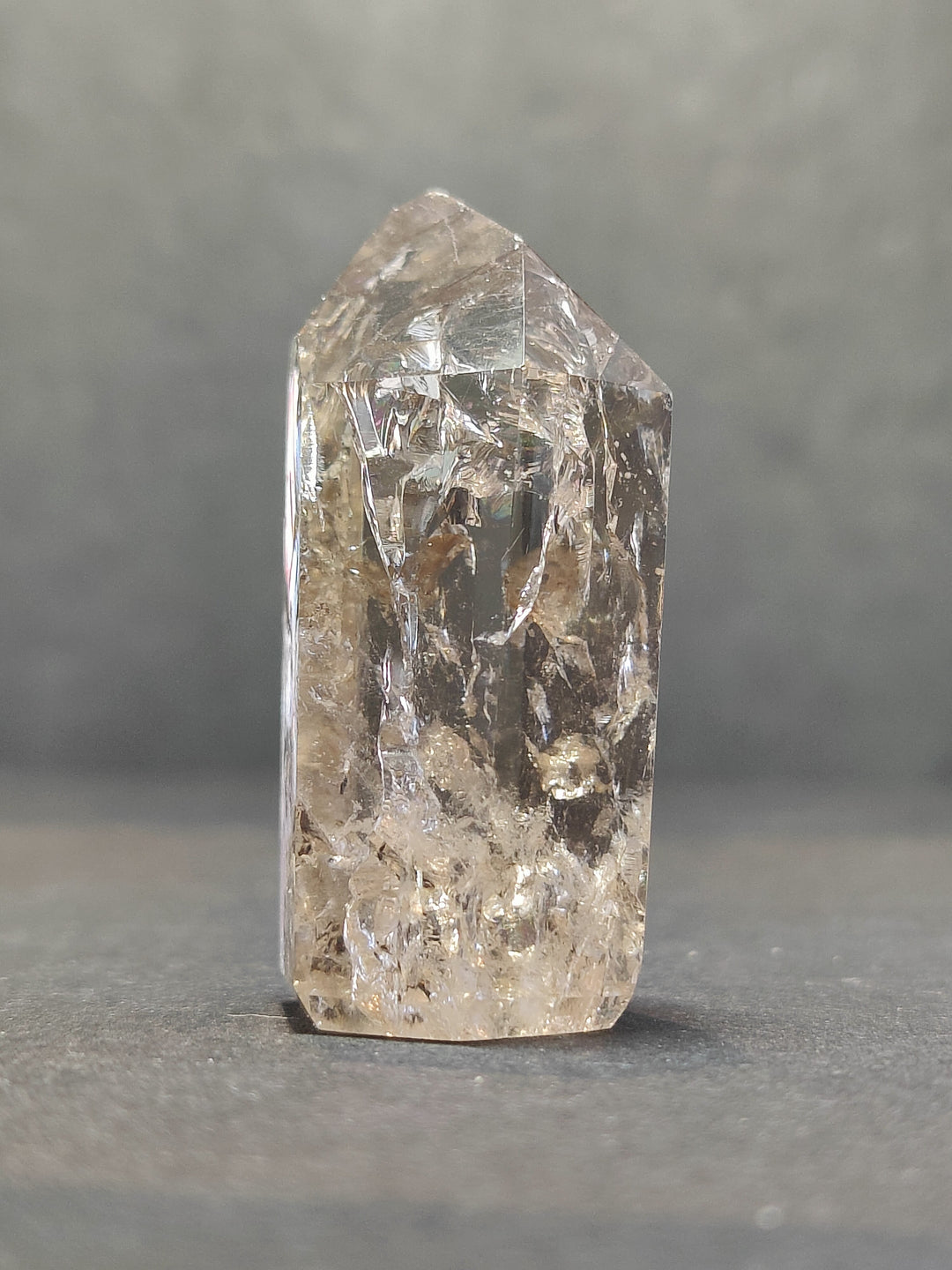 Single tall quartz point with clear crystal body and smoky golden inclusions