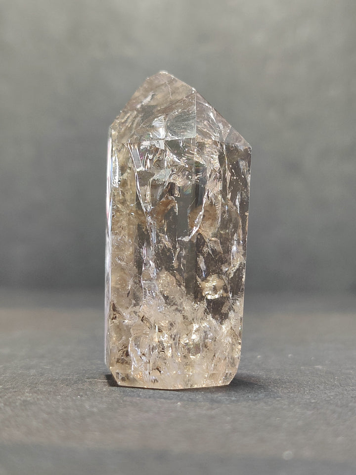 Single tall quartz point with clear crystal body and smoky golden inclusions