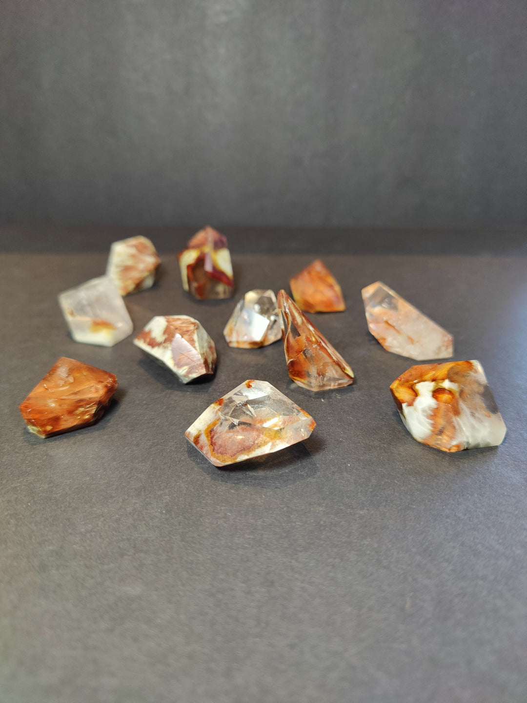Polished freeform quartz crystal pieces, scattered mix of orange and clear stones.