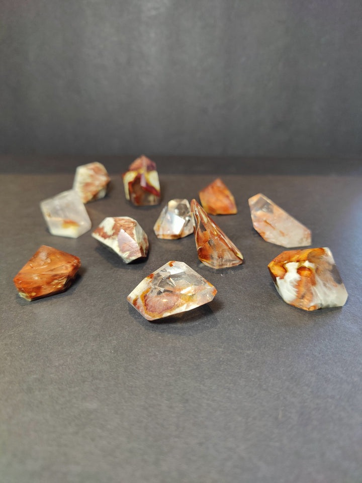 Polished freeform quartz crystal pieces, scattered mix of orange and clear stones.