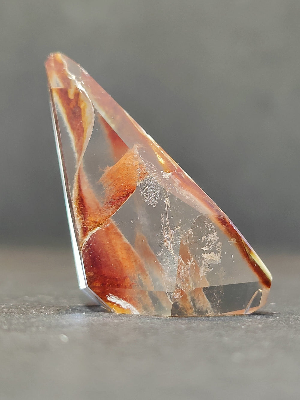 Polished freeform quartz crystal, orange and clear triangular faceted stone.