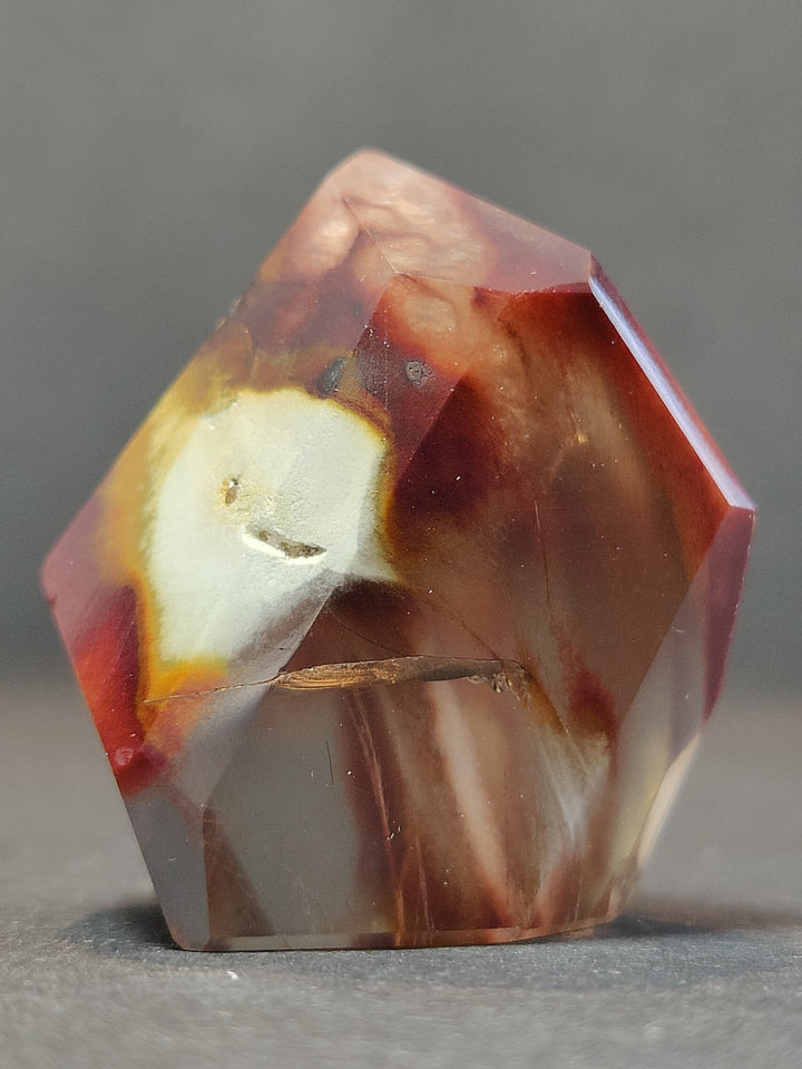 Polished freeform quartz crystal, red-orange and milky white with clear facets.