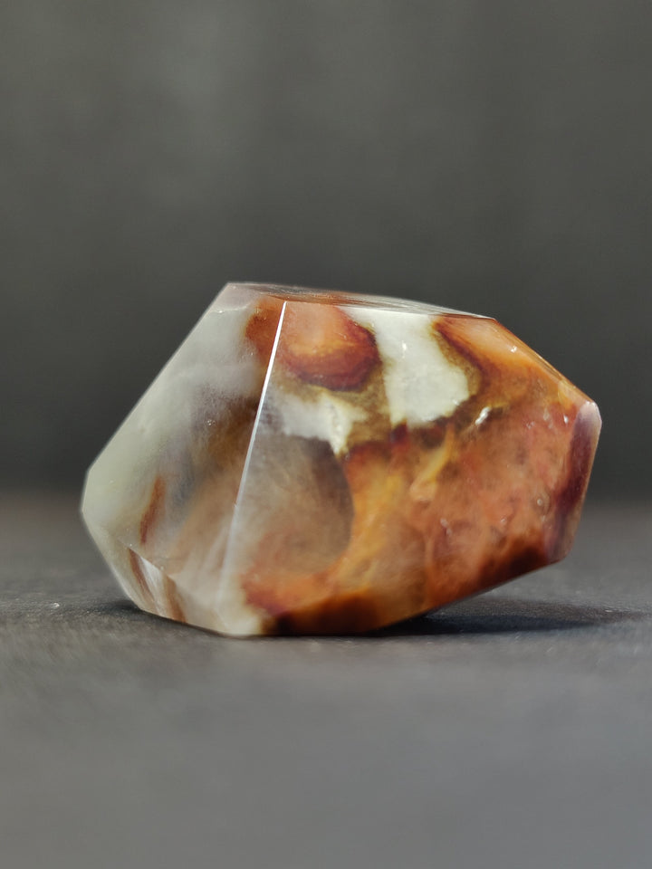 Polished freeform quartz crystal, cube-like shape in white with amber orange patches.
