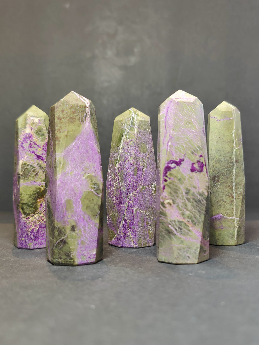 Polished crystal tower sculptures, pale green with purple streaks and mottled texture, pointed tops