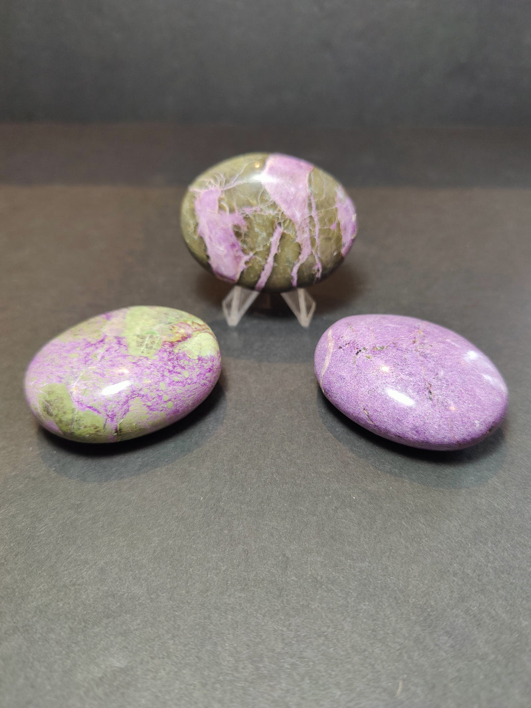 Polished purple and green gemstone heart and palmstone sculptures on clear stands