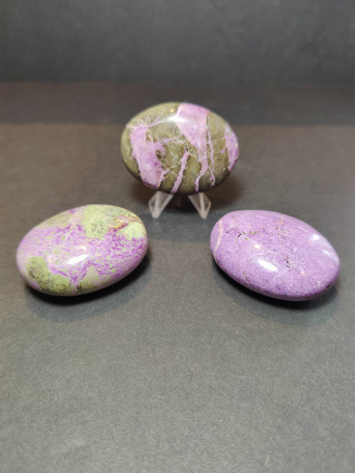 Polished purple and green gemstone heart and palmstone sculptures on clear stands
