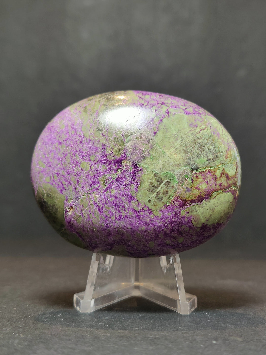 Polished purple and green gemstone palmstone sculpture on clear stand