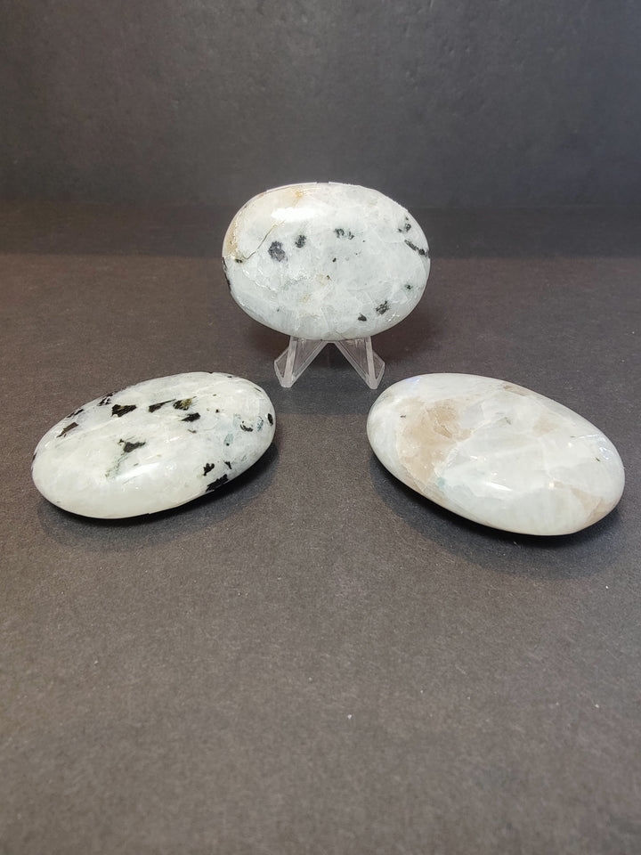 Moonstone heart with two palmstones on clear display stands