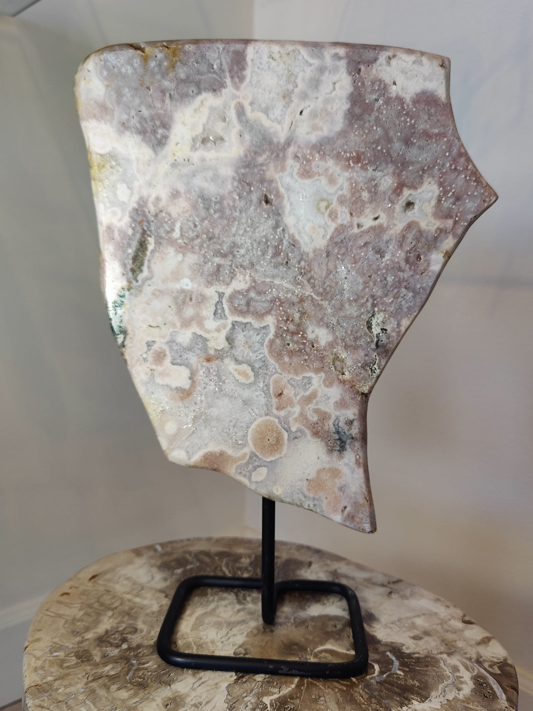 Polished pink amethyst slab sculpture on black metal display stand