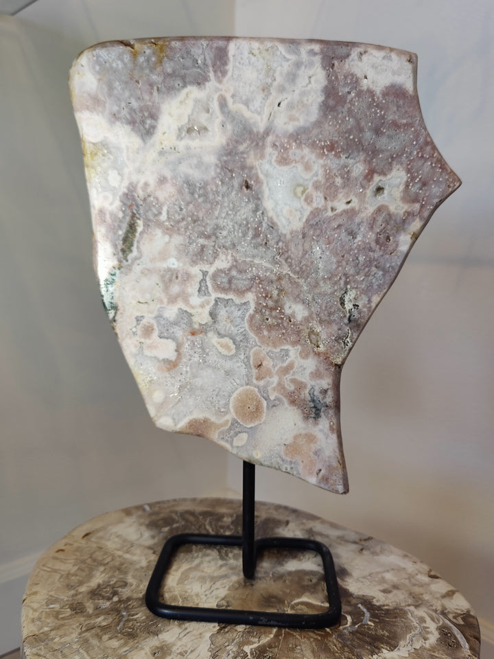 Polished pink amethyst slab sculpture on black metal display stand