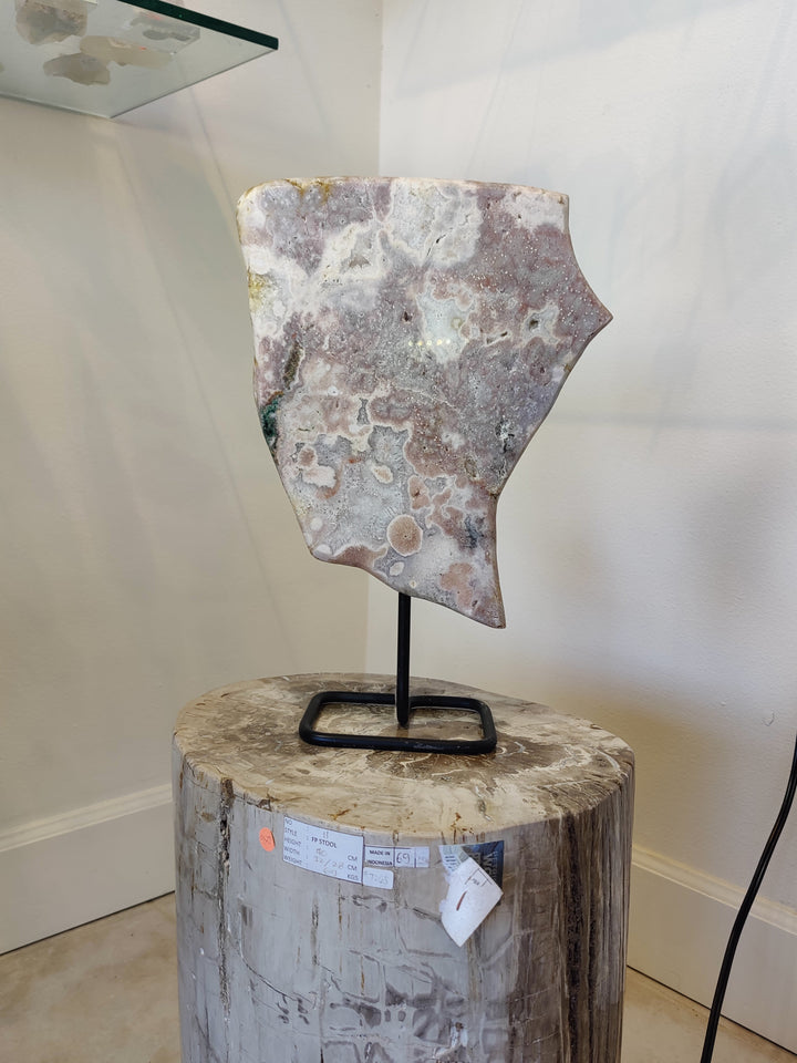 Polished pink amethyst slab sculpture on black metal stand with round base