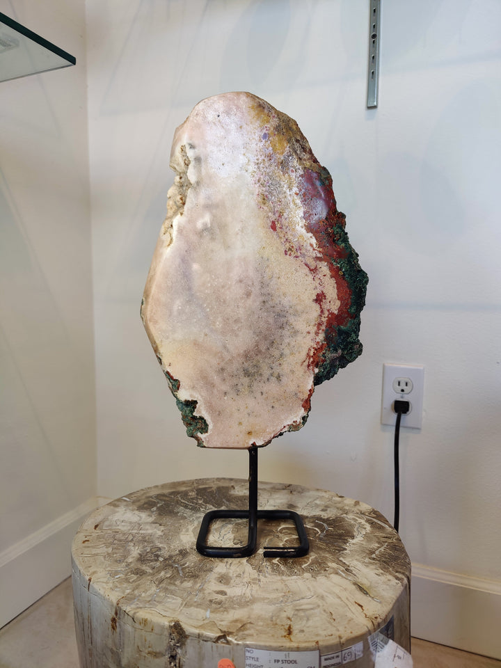 Pink amethyst slab sculpture with green and red edges on black metal stand