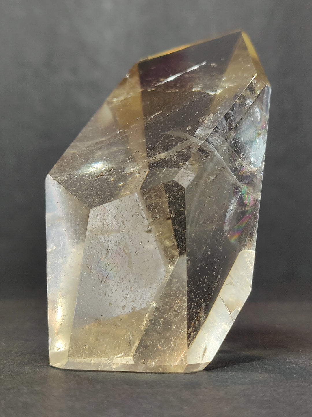 Clear smoky quartz free-form sculpture, faceted polished surface with rainbow flecks